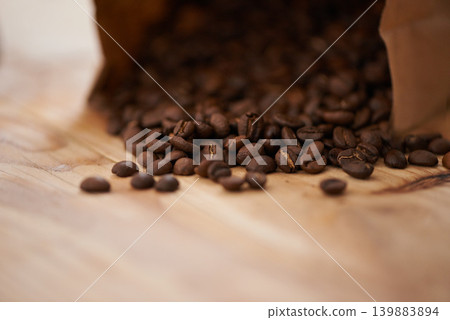 Table, closeup and fresh roasted coffee beans, spilling from a paper bag onto a vintage wood counter with copy space. Studio, aromatic bitter caffeine to feel refreshed with hot, refreshing beverage Table, closeup and fresh roasted coffee beans, spilling from a paper bag onto a vintage wood counter with copy space. Studio, aromatic bitter caffeine to feel refreshed with hot, refreshing beverage 139883894