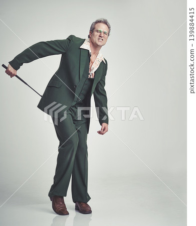 Mature, man and fashion with whip in studio with suit on grey background and vintage look. Tuxedo, elegance and retro with riding crop and formal in expensive clothes, classy and fashionable 139884415