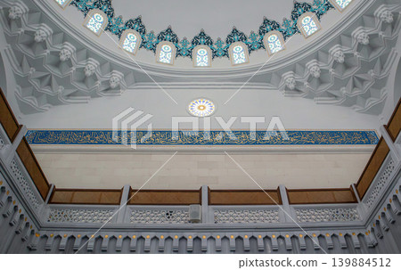 The structure features high arches adorned with intricate Islamic geometric designs. Vibrant blue patterns create a visual impact within the prayer hall. The structure features high arches adorned with intricate Islamic geometric designs. Vibrant blue patterns create a visual impact within the prayer hall. 139884512