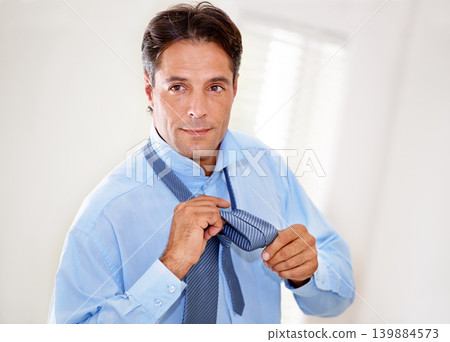 Home, tying tie and businessman getting ready for career, job or entrepreneur preparation in the morning. Face, professional and dressing for work, serious person wear necktie or consultant in house Home, tying tie and businessman getting ready for career, job or entrepreneur preparation in the morning. Face, professional and dressing for work, serious person wear necktie or consultant in house 139884573