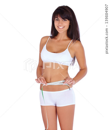 Woman, body and measure tape in studio for fitness, health and weight loss results of training progress. Portrait of model or person check stomach for exercise or workout goals on a white background Woman, body and measure tape in studio for fitness, health and weight loss results of training progress. Portrait of model or person check stomach for exercise or workout goals on a white background 139884907