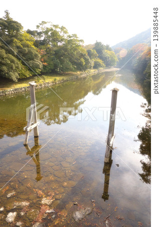 The scenery of the clear Isuzu River flowing through the Inner Shrine of Ise Grand Shrine and the wooden support posts of Uji Bridge. The scenery of the clear Isuzu River flowing through the Inner Shrine of Ise Grand Shrine and the wooden support posts of Uji Bridge. 139885448