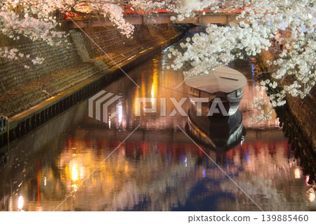 The evocative beauty of Japan: A portrait of a riverside at night, enveloped in cherry blossoms in full bloom. The evocative beauty of Japan: A portrait of a riverside at night, enveloped in cherry blossoms in full bloom. 139885460