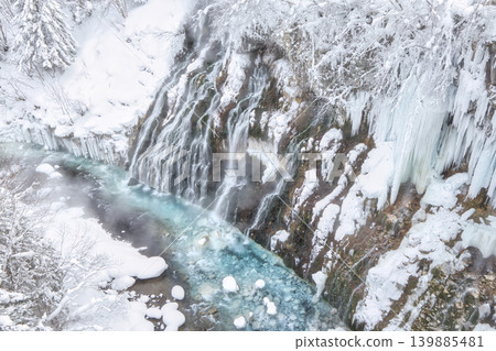 The magnificent Shirahige Falls, enveloped in a snowy landscape; the cobalt blue winter Blue River. The magnificent Shirahige Falls, enveloped in a snowy landscape; the cobalt blue winter Blue River. 139885481