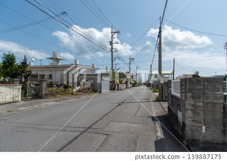 A long, straight street lined with utility poles, with the shadows of the power lines cast in the middle of the road, and no cars or people passing by. A long, straight street lined with utility poles, with the shadows of the power lines cast in the middle of the road, and no cars or people passing by. 139887175