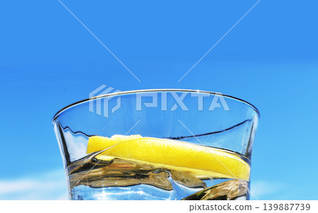Blue sky and a glass of mineral water with lemon. Blue sky and a glass of mineral water with lemon. 139887739