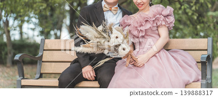 Couple taking wedding photos on a park bench Couple taking wedding photos on a park bench 139888317