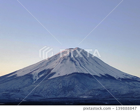 Under the clear winter morning sky, which changes from white to blue, the majestic Mount Fuji stands majestically with its base spreading out. Under the clear winter morning sky, which changes from white to blue, the majestic Mount Fuji stands majestically with its base spreading out. 139888847