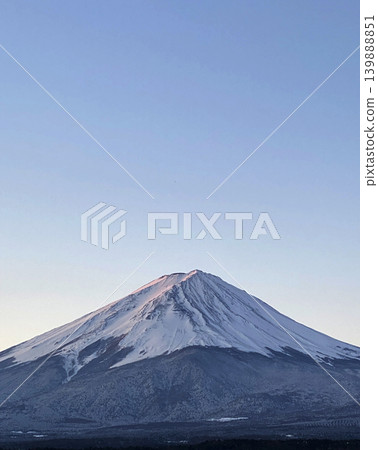 在晴朗的冬日清晨,天空由白轉藍,神聖的富士山巍峨聳立,山腳下一片純白。 在晴朗的冬日清晨,天空由白轉藍,神聖的富士山巍峨聳立,山腳下一片純白。 139888851