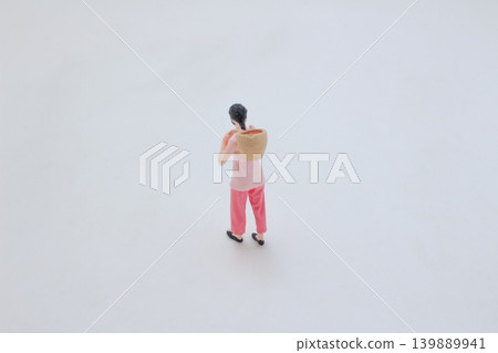 Miniature figure carrying basket on shoulder walking Miniature figure carrying basket on shoulder walking 139889941