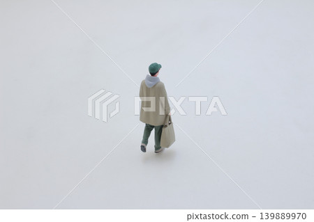 Miniature figure walking forward carrying bag Miniature figure walking forward carrying bag 139889970