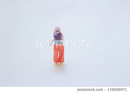 Miniature pedestrian holding drink wearing colorful outfit Miniature pedestrian holding drink wearing colorful outfit 139889971