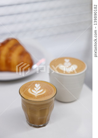 Cup of hot milk piccolo latte coffee and hot cappucino with croissant on white table. Cup of hot milk piccolo latte coffee and hot cappucino with croissant on white table. 139890182