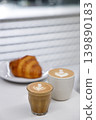 Cup of hot milk piccolo latte coffee and hot cappucino with croissant on white table. 139890183