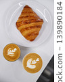 Cup of hot milk piccolo latte coffee and hot cappucino with croissant on white table. 139890184