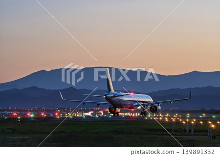 Sendai Airport at dusk, with a taxiing airplane and the Zao mountain range in the background, Natori City, Miyagi Prefecture. 139891332