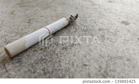 Close-up photography of a lit cigarette on a concrete surface. Close-up photography of a lit cigarette on a concrete surface. 139891425