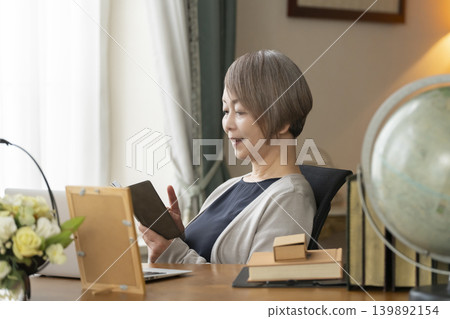 Senior woman working remotely from her home office Senior woman working remotely from her home office 139892154