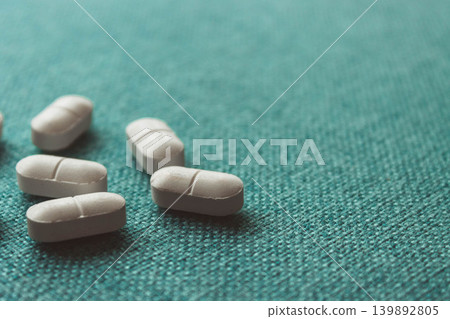 White Pills On Teal Fabric Background White Pills On Teal Fabric Background 139892805