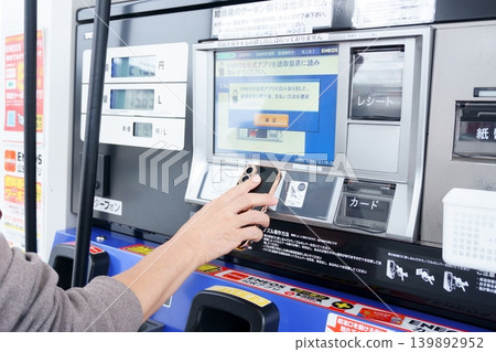 The hands of a man operating a gas pump at a gas station 139892952