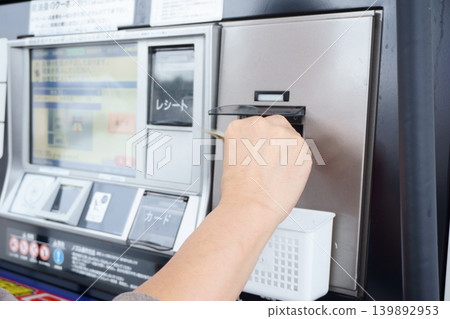 A man's hands as he pays at a gas pump. 139892953