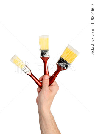 three brushes in a raised hand isolated on a white background three brushes in a raised hand isolated on a white background 139894669