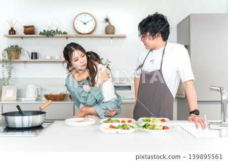 一對夫婦正在廚房做飯,母親抱著他們挑食的女兒(挑食,挑食)。 一對夫婦正在廚房做飯,母親抱著他們挑食的女兒(挑食,挑食)。 139895561