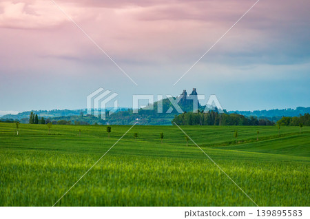 Dramatic sunset panorama of Cesky Raj landscape in Czech Republic with Trosky castle ruins on volcanic rocks beneath storm clouds glowing with sunset colors Dramatic sunset panorama of Cesky Raj landscape in Czech Republic with Trosky castle ruins on volcanic rocks beneath storm clouds glowing with sunset colors 139895583