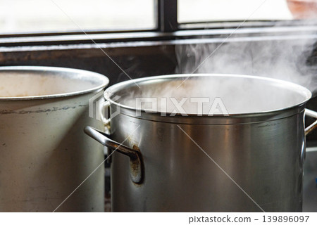 窗邊放著一口冒著熱氣的大鍋,正在準備烹飪。 窗邊放著一口冒著熱氣的大鍋,正在準備烹飪。 139896097