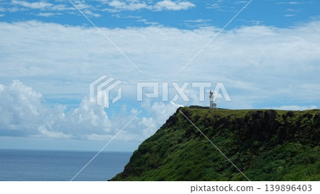 A lighthouse on a cape and a blue sky A lighthouse on a cape and a blue sky 139896403