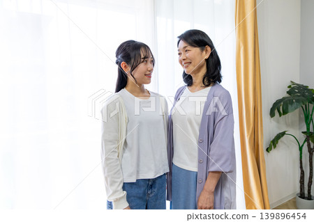 A mother and daughter who are close and gaze at each other. 139896454