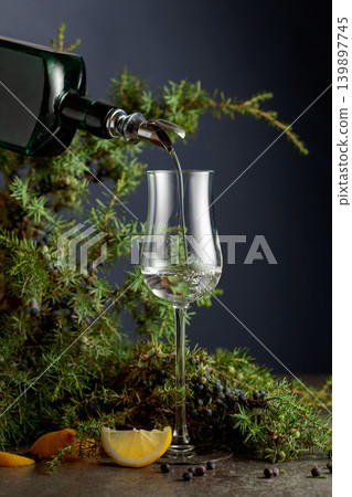 Gin is poured from a vintage bottle into a glass. Gin is poured from a vintage bottle into a glass. 139897745