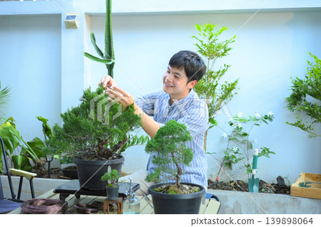A man making bonsai pruning with precision care and craftsmanship 139898064