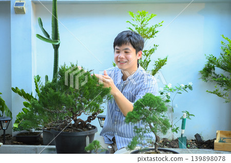 A man making bonsai pruning with precision care and craftsmanship A man making bonsai pruning with precision care and craftsmanship 139898078