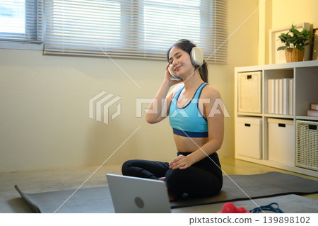 Woman enjoying music with headphones after workout at home, calm wellness lifestyle moment Woman enjoying music with headphones after workout at home, calm wellness lifestyle moment 139898102