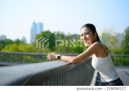 Smiling woman resting after workout on park bridge, healthy lifestyle Smiling woman resting after workout on park bridge, healthy lifestyle 139898117