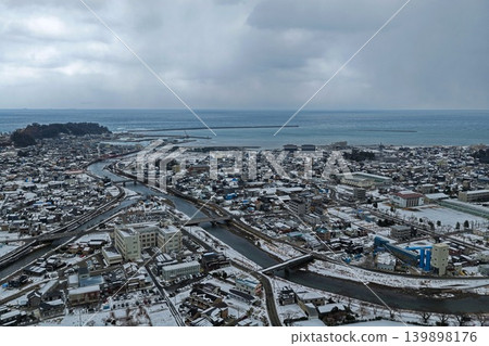 A winter aerial photograph overlooking the snowy landscape and port town of Wajima City, Ishikawa Prefecture. A winter aerial photograph overlooking the snowy landscape and port town of Wajima City, Ishikawa Prefecture. 139898176