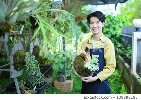 Male gardener holding staghorn fern, showcasing plant care, pride, and botanical expertise 139898183