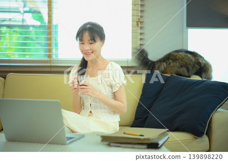 Young woman enjoys coffee and works on laptop at home. 139898220