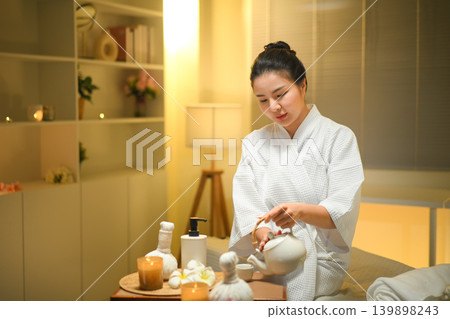 Woman pouring herbal tea in spa setting with warm light and calm wellness mood Woman pouring herbal tea in spa setting with warm light and calm wellness mood 139898243