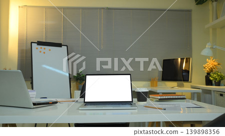 Office workspace with laptop mockup on desk and evening lighting Office workspace with laptop mockup on desk and evening lighting 139898356
