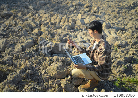 Farmer analyzing soil sample with laptop in dry field Farmer analyzing soil sample with laptop in dry field 139898390