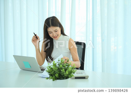 Professional woman reading financial documents at modern office desk 139898426