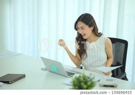 Businesswoman celebrating positive financial report Businesswoman celebrating positive financial report 139898455