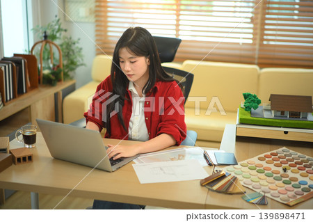 Architect working on laptop with material samples and house model Architect working on laptop with material samples and house model 139898471