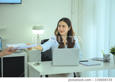 Businesswoman handing financial documents to colleague Businesswoman handing financial documents to colleague 139898536