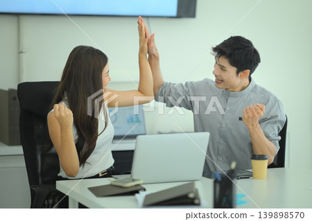 Colleagues high five after achieving business goal in the meeting room Colleagues high five after achieving business goal in the meeting room 139898570
