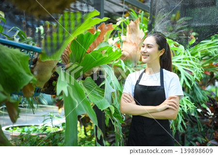 Confident gardener woman standing in plant nursery Confident gardener woman standing in plant nursery 139898609