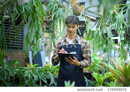 Gardener using digital tablet in staghorn fern greenhouse Gardener using digital tablet in staghorn fern greenhouse 139898656