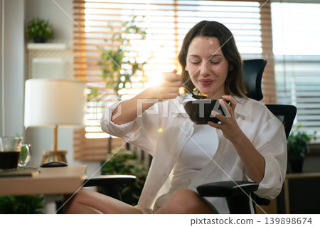 Remote worker eating breakfast while sitting at computer workspace. Remote worker eating breakfast while sitting at computer workspace. 139898674
